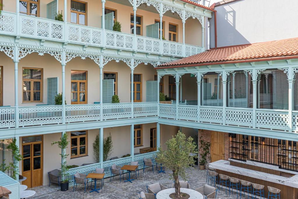 第比利斯The House Hotel Old Tbilisi的一座带庭院的建筑,配有桌椅
