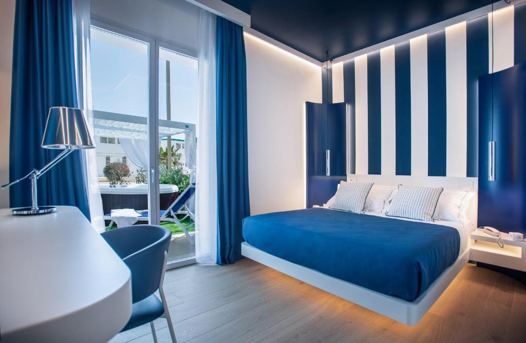 卡利亚里诺迪鲁斯酒店的蓝色和白色的卧室配有一张床和一张书桌