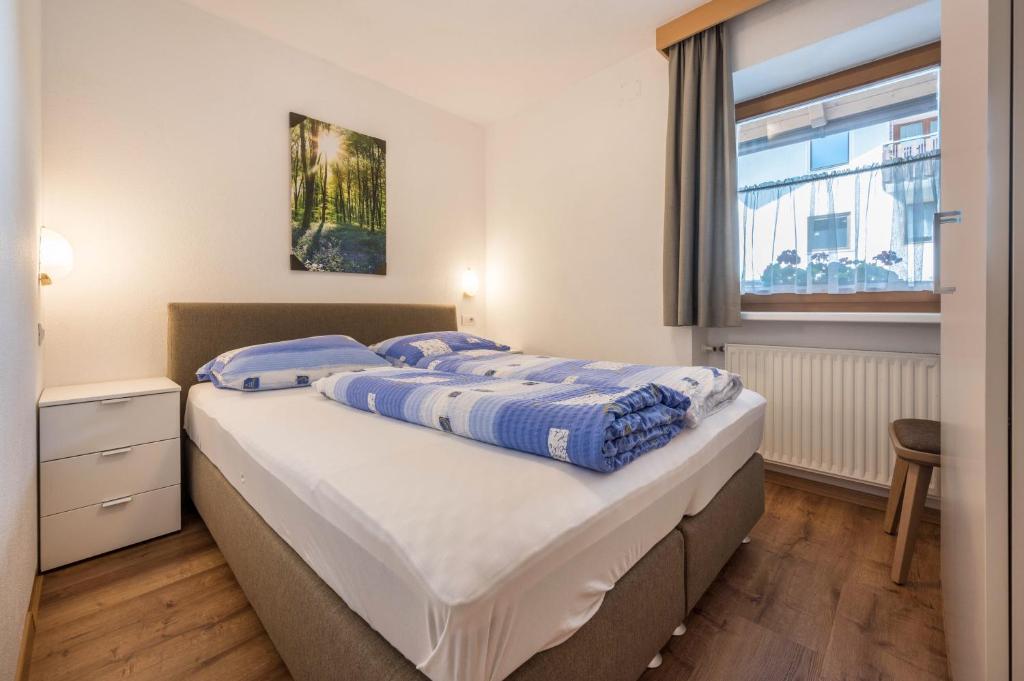 卢塔戈App Sonne Nr 16的一间卧室配有一张带蓝色床单的床和一扇窗户。