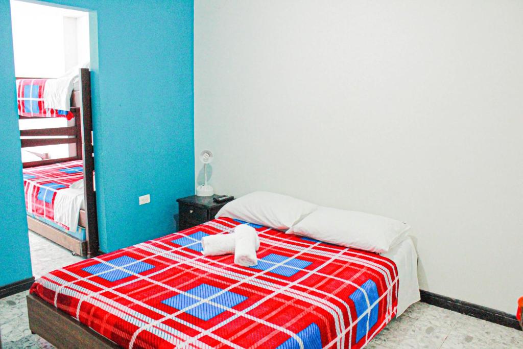 马尼萨莱斯El Cable Hostal的一间卧室配有一张带红色和蓝色毯子的床