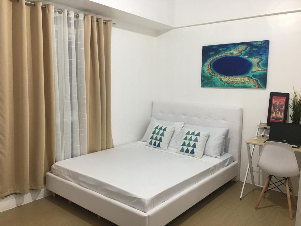 马尼拉Budget Friendly-Spacious One Bedroom Suite Opposite to Naia 3的卧室配有白色的床、窗帘和书桌