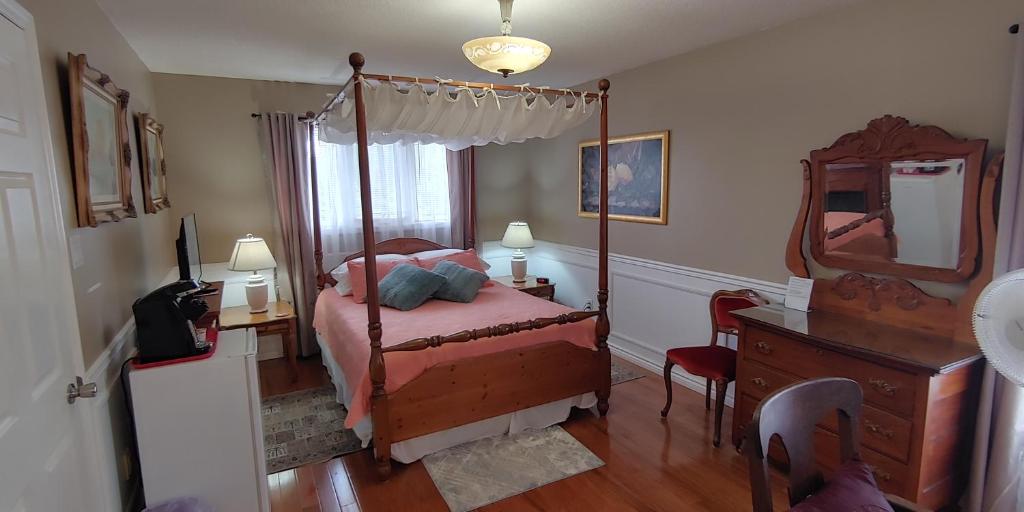 卡沃萨湖BobcaygeonB&B的一间卧室配有一张带镜子和梳妆台的天蓬床