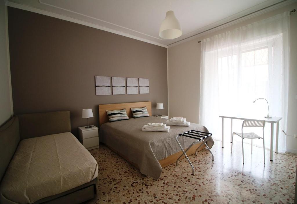 卡塔尼亚Giuffrida Apartment Rooms的一间卧室配有一张床、一张桌子和一个窗户。