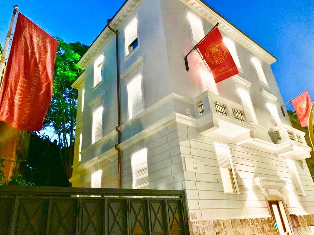 罗马玛格丽塔女王酒店的白色的建筑,上面有两面红旗