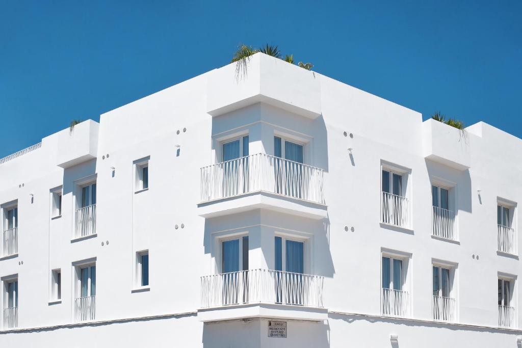 科尼尔-德拉弗龙特拉Rio Salado Conil Hostal的带阳台的白色建筑和蓝天