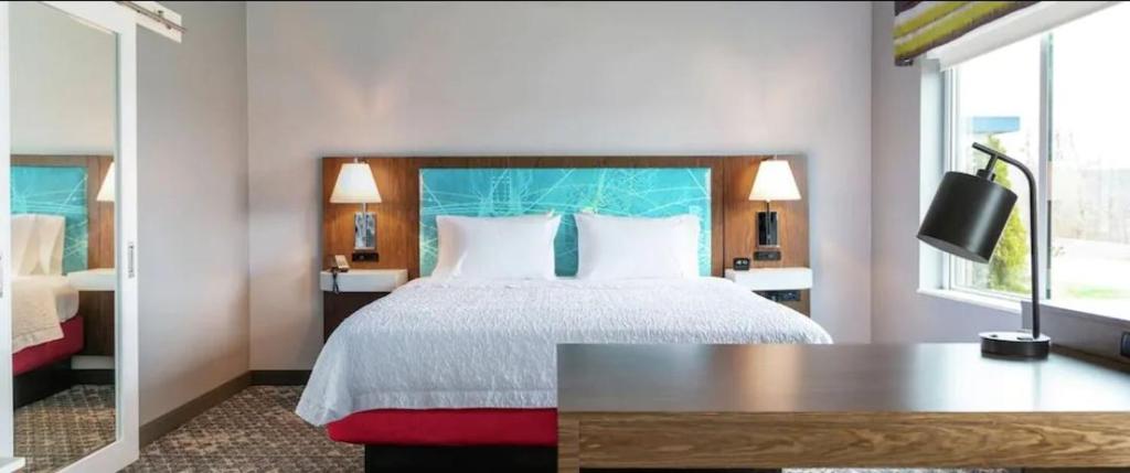 HowellHampton Inn & Suites Howell的一间卧室配有一张带桌子和窗户的床