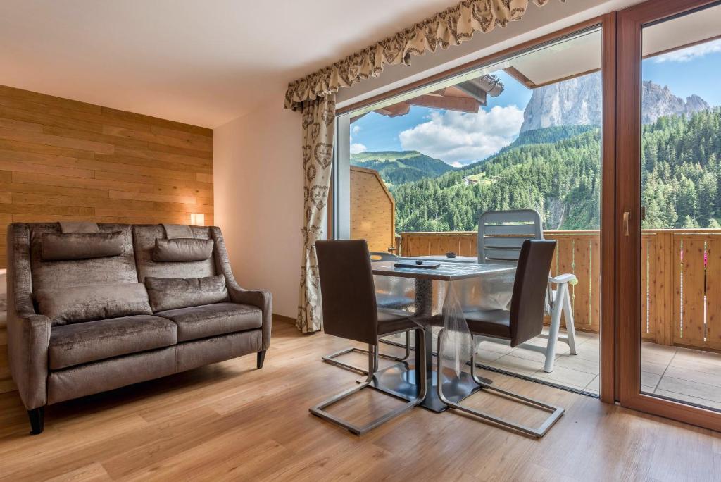 圣克里斯蒂娜Garni Hotel Gardena App Dolomites 3的客厅配有玻璃桌和沙发