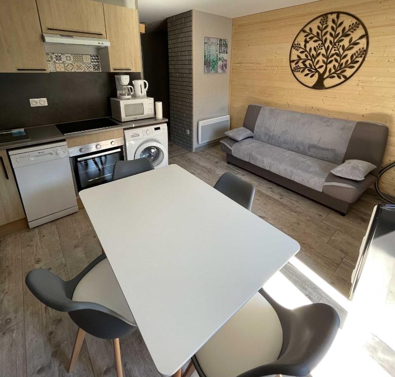勒蒙多尔Le Martin pêcheur, Appartement proche hyper centre的厨房以及带白色桌椅的起居室。