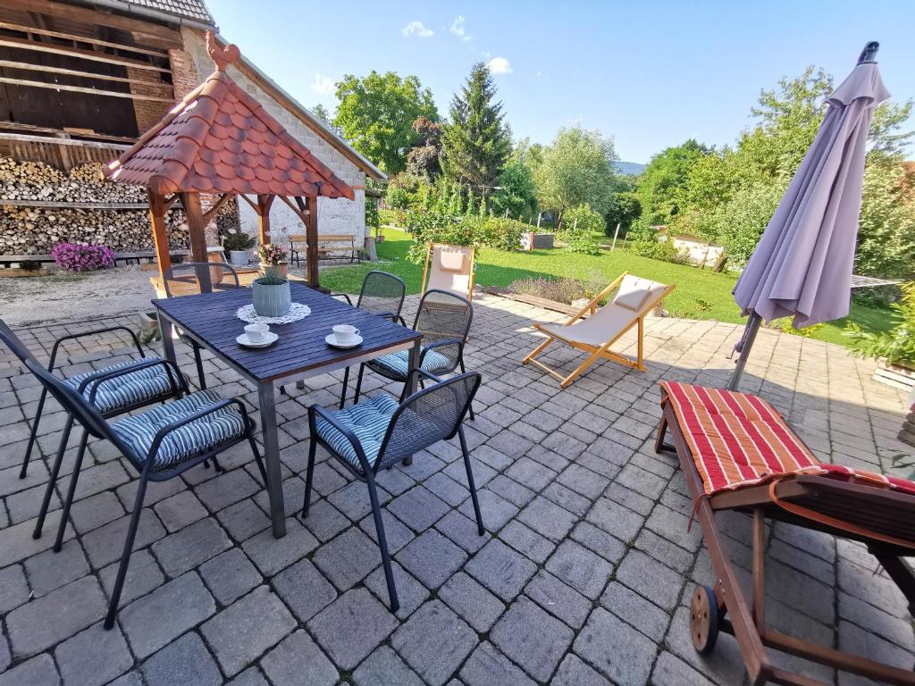 斯洛文尼亚科尼采Charming village house with patio and garden的庭院配有桌椅和遮阳伞。
