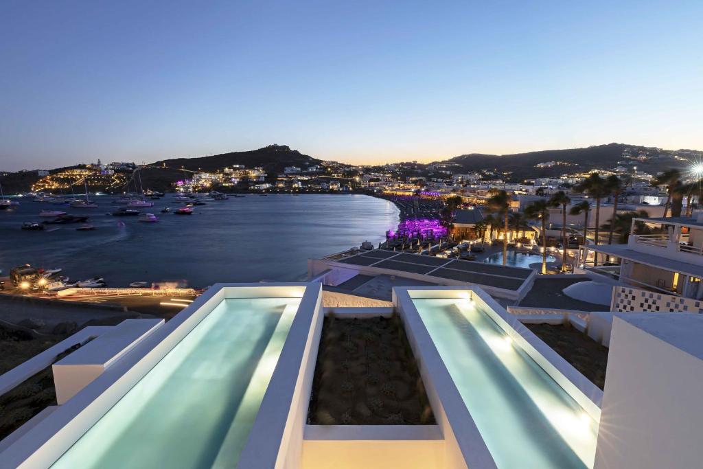 奥诺斯CUBIC Mykonos Seafront Design Suites的一座带两个游泳池的建筑享有水景
