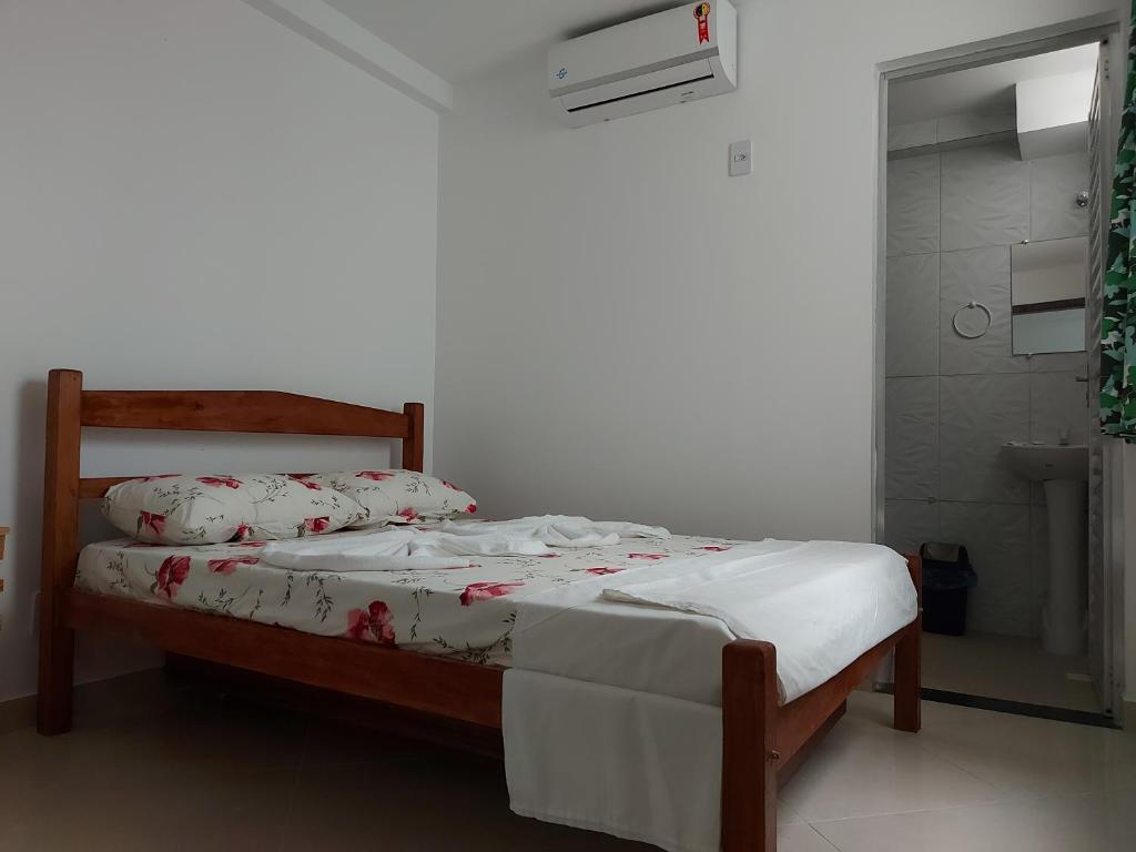 萨尔瓦多Casarão Nazaré Hostel的一间卧室配有白色床单和红色鲜花。