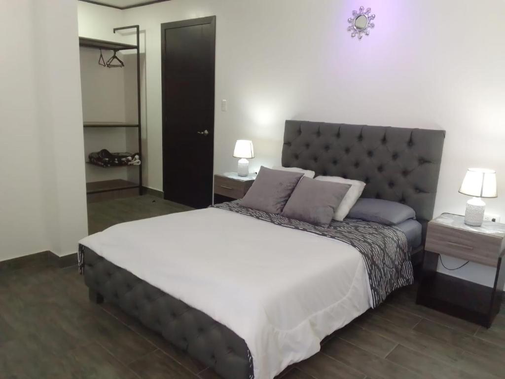 安巴托Jardines Ambato的一间卧室配有一张大床、两张桌子和两盏灯。