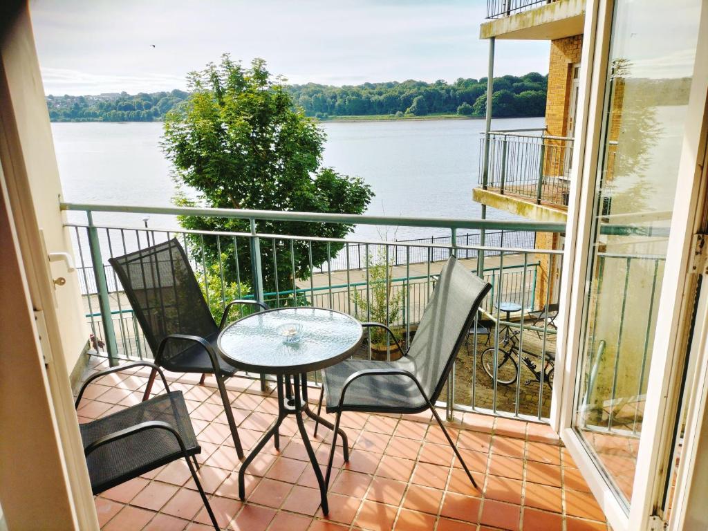 伦敦德里Derry-Londonderry city centre waterfront appartment的阳台配有桌椅,享有水景。