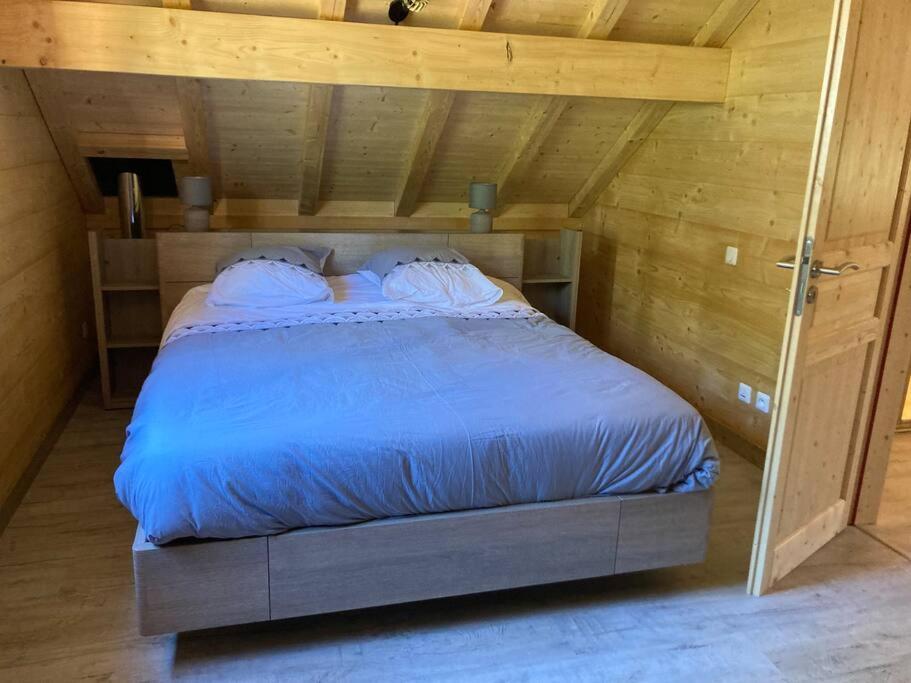AlièzeForest Jura Lodge - Chalet des sapins的木制客房内的一间卧室,配有一张床