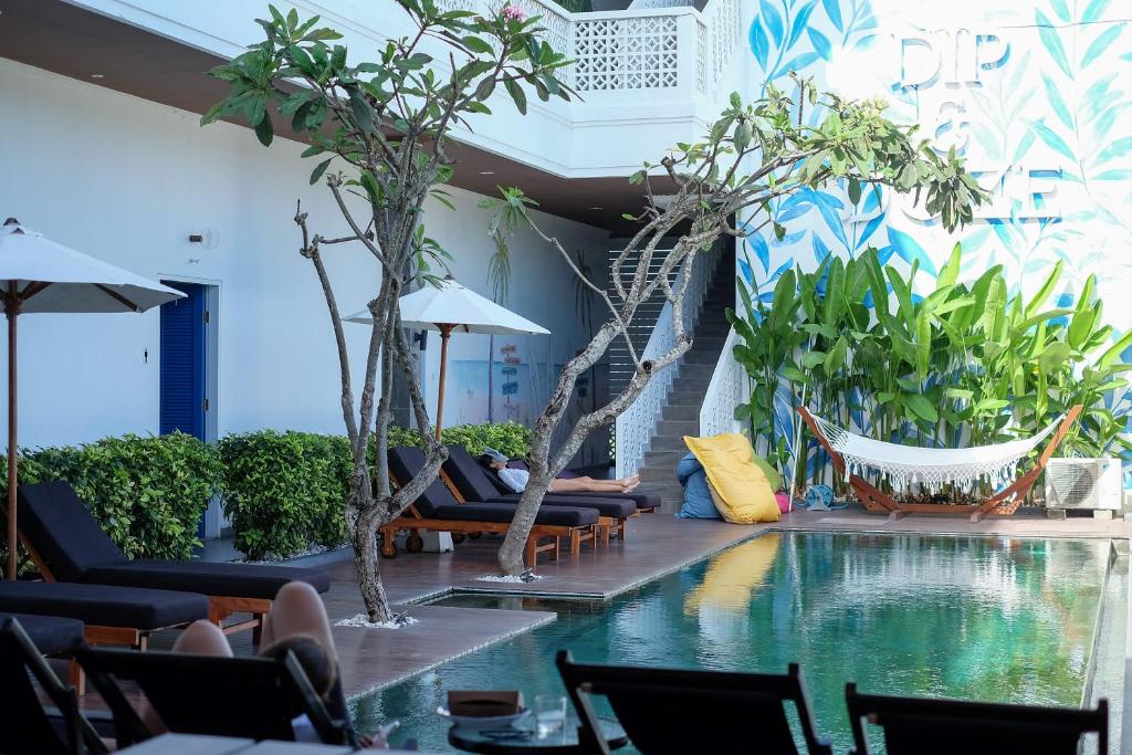 坎古Dip & Doze Boutique Hostel的酒店大堂设有游泳池、椅子和树木