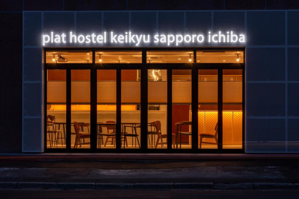 札幌plat hostel keikyu sapporo ichiba的餐厅的窗户,里面摆放着椅子