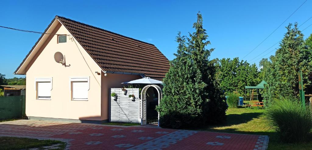 KőröshegyÖnálló, klimatizált, medencés nyaraló a Balatonnál!的一座白色的小建筑,在院子里有一扇门