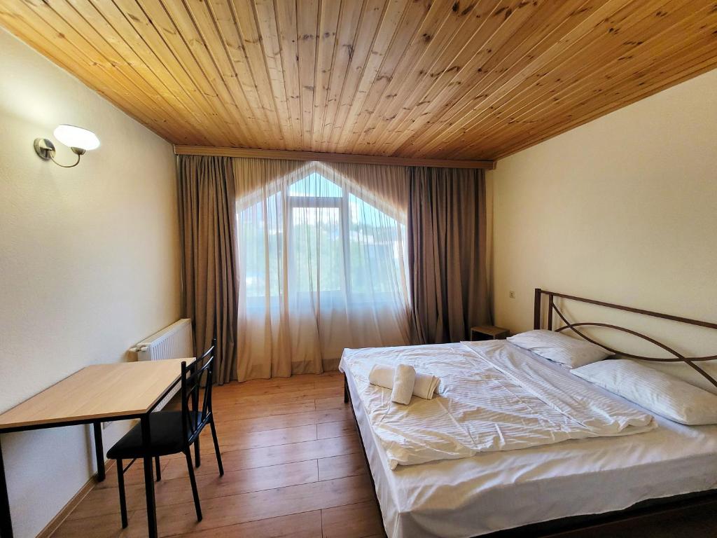 第比利斯Homelike B&B的一间卧室配有一张床、一张桌子和一个窗户。