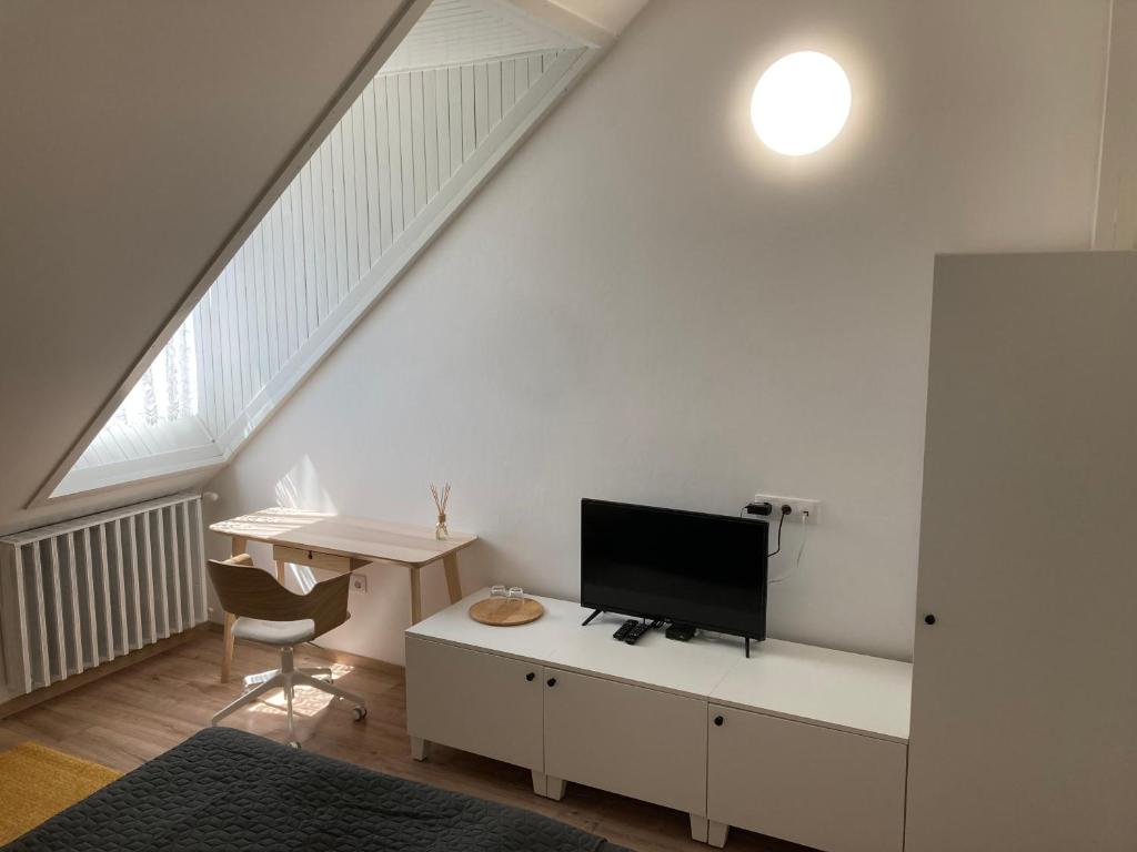 BólyBólyi Panzió的一间白色的房间,配有一张书桌和一台电视机