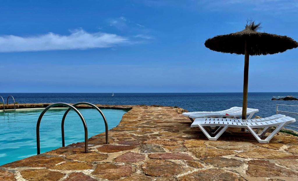 巴古尔Cap Sa Sal - Sa Roca 3的游泳池旁的两把椅子和一把遮阳伞