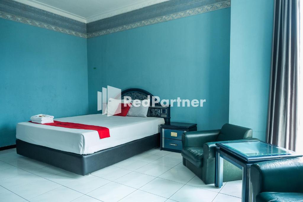 日惹Akur Hotel Malioboro Mitra RedDoorz的一间卧室配有一张床、一把椅子和一张桌子