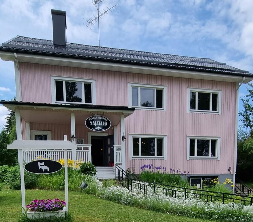 皮耶克赛迈基Wanha Neuvola Guesthouse & Apartment的粉红色的房子,前面有标志