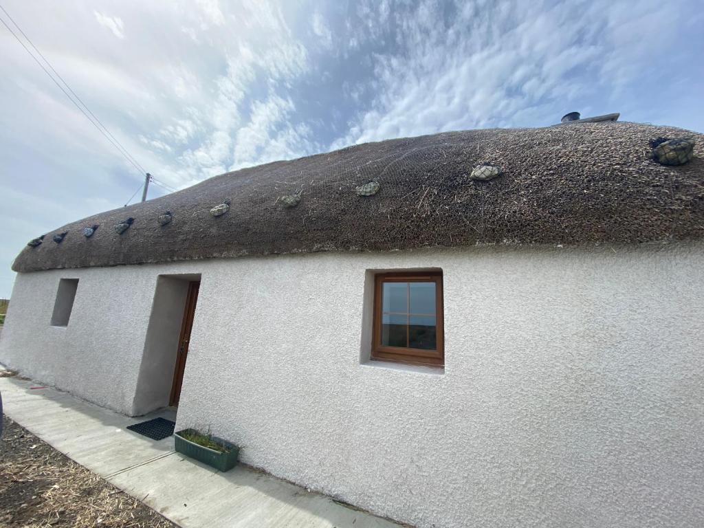 CreagorryAn Taigh Dubh- One bedroomed cottage的白色的建筑,茅草屋顶,窗户