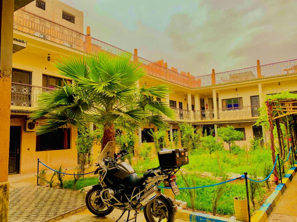 廷吉尔卡斯巴餐厅酒店的停在一座棕榈树建筑前面的摩托车