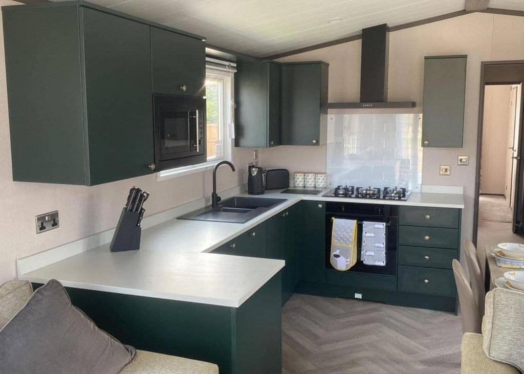 EatonLadera Retreat Lodges的厨房配有绿色橱柜和白色台面