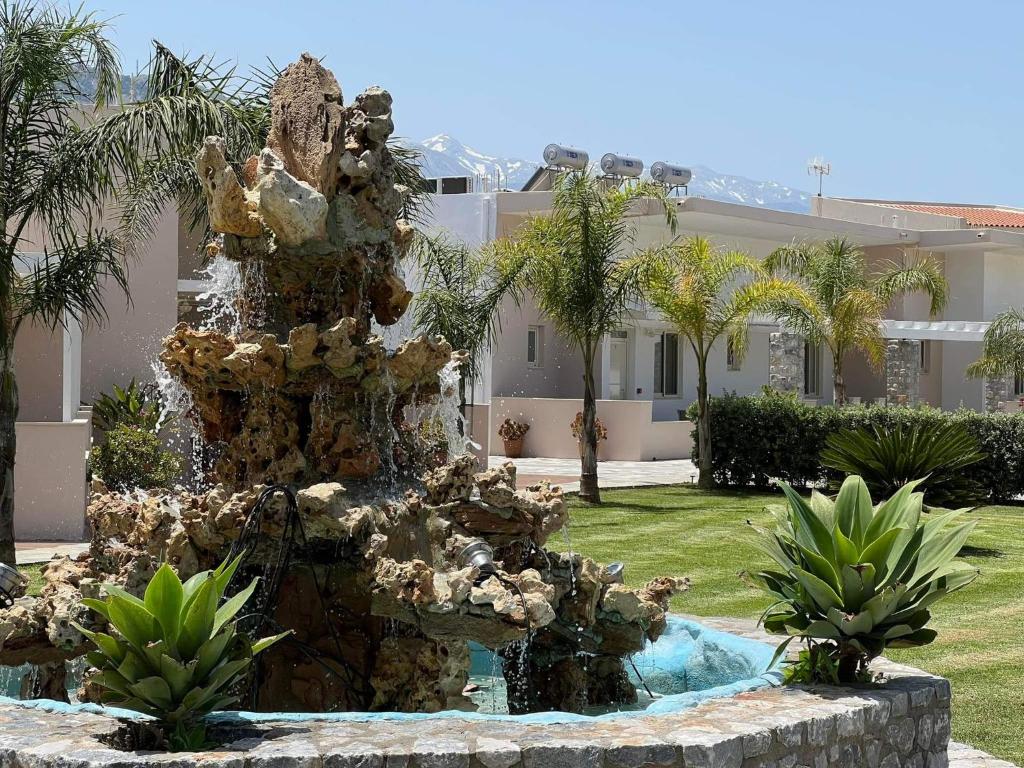 耶奥伊乌波利斯Argiri Apartments & Suites的棕榈树屋前的喷泉