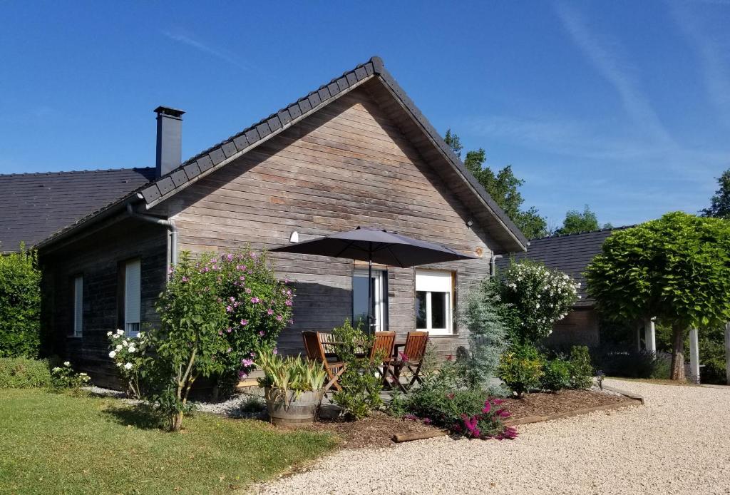 Saint-AulaireGîte de la Tuillère, maison contemporaine en bois avec vue et piscine的一座房子,配有两把椅子和一把伞