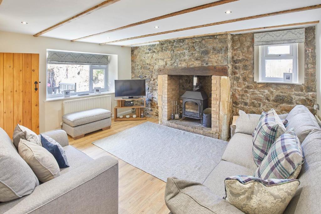 Holy IslandHost & Stay - Eden Cottage的带沙发和壁炉的客厅