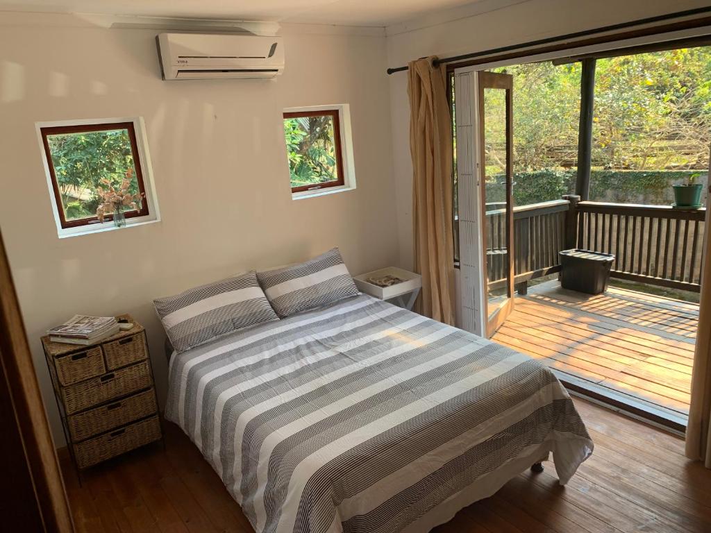 LobambaJackalberry Cottage的一间卧室设有一张床和一个滑动玻璃门