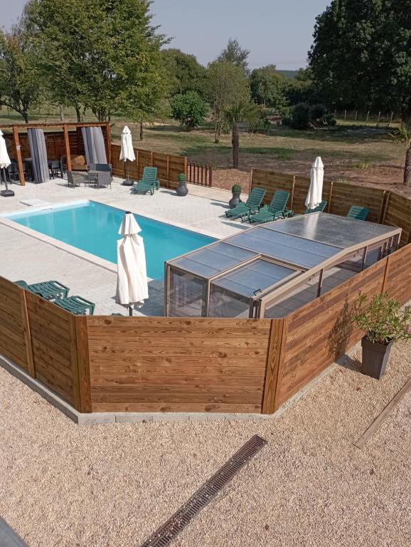 SoudanLes gîtes du petit Marcel的一个带木制甲板和游泳池的游泳池