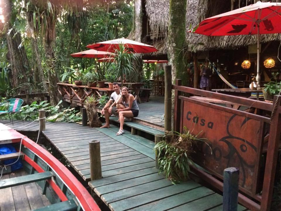 里约杜尔塞Hotel Casa Perico的两人坐在带遮阳伞的木甲板上