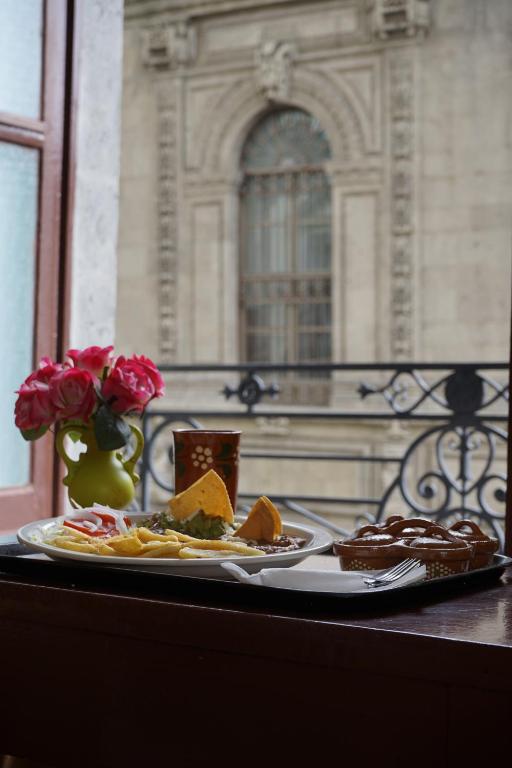 墨西哥城伊莎贝尔酒店的一张桌子,上面有两盘食物和一瓶玫瑰花