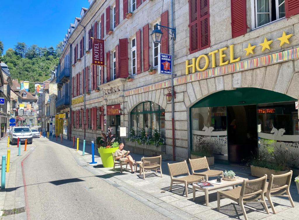 奥比松Hôtel Le France的坐在酒店前面的长凳上的人