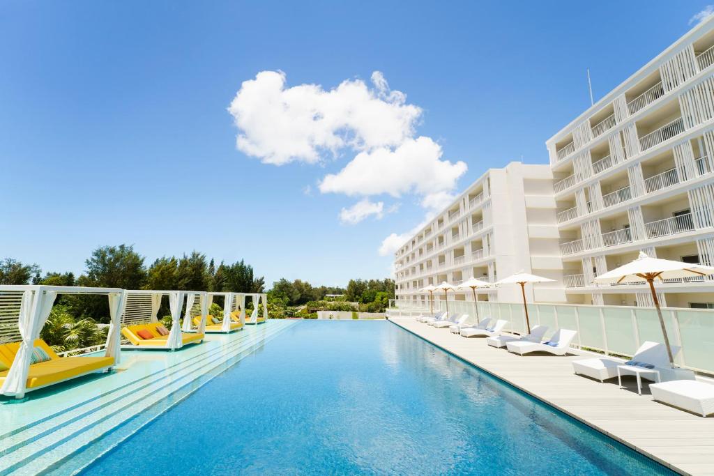 恩纳Hoshino Resorts BEB5 Okinawa Serakaki的游泳池,带椅子和遮阳伞
