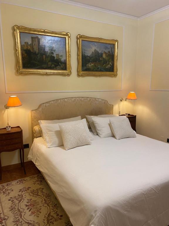 博洛尼亚Rooftop Garden的卧室配有白色的床和墙上的两张照片