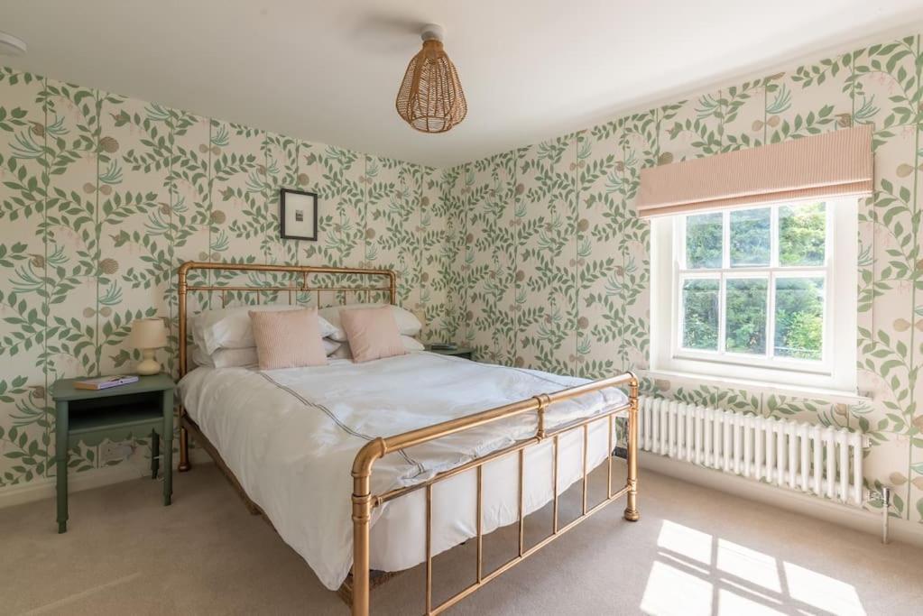 马尔堡The Cottage in the Clouds的一间卧室配有一张带绿色和白色壁纸的床