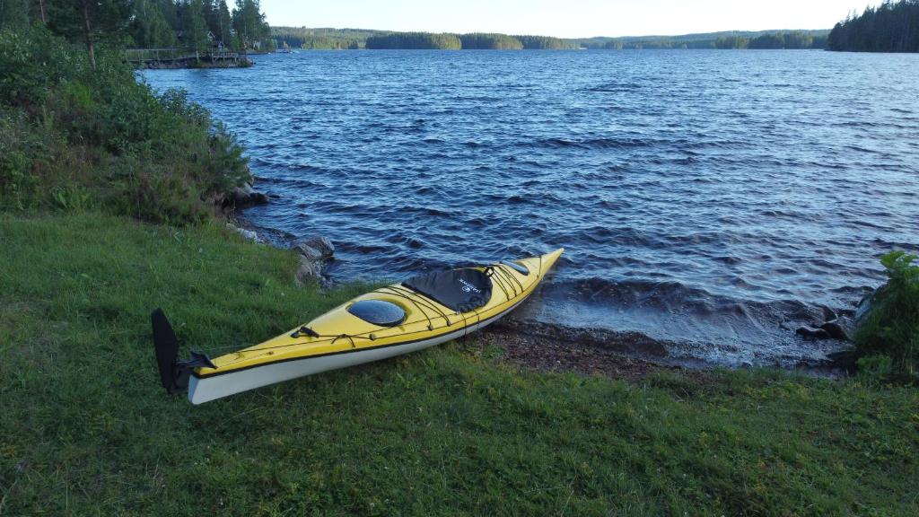 RämshyttanRämsbyns Fritidsby的坐在湖岸上的黄色皮艇