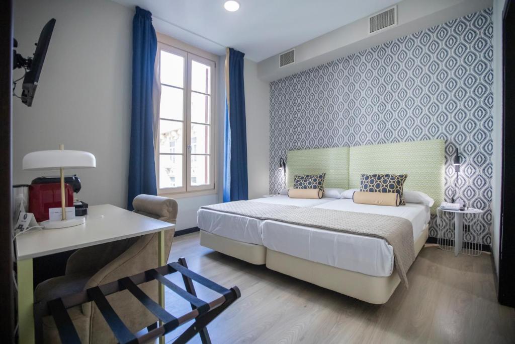 马拉加马拉加苏豪精品酒店的一间卧室配有一张床、一张桌子和一张书桌