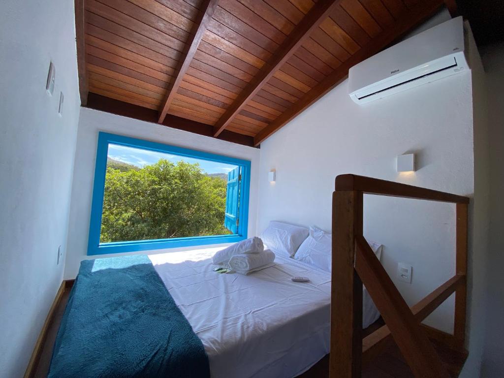 皮雷诺波利斯Espaço Tropicália的一间卧室设有一张大床和大窗户