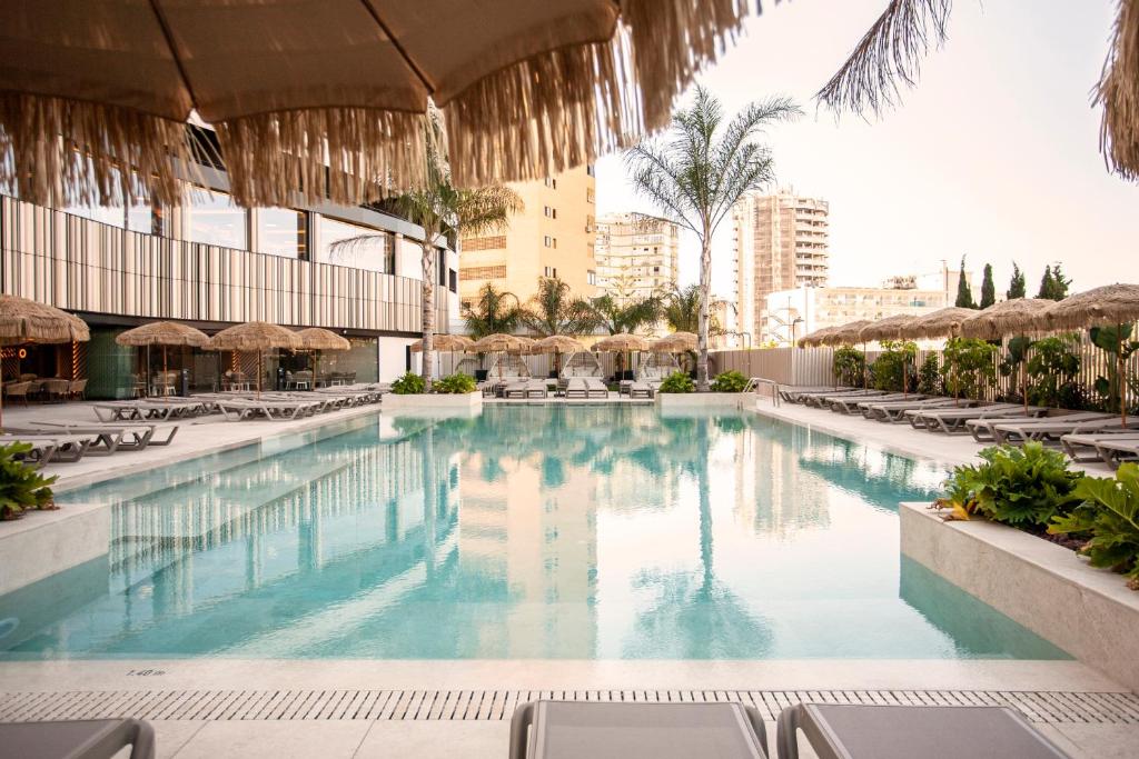 贝尼多姆Hotel Primavera Park的度假村的游泳池,配有椅子和遮阳伞