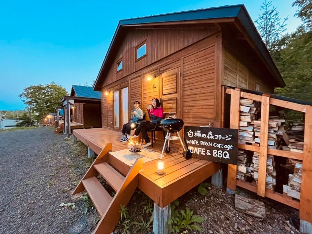 网走市Shirakaba no mori Cottage - Vacation STAY 90794v的两个人坐在一个小房子的甲板上