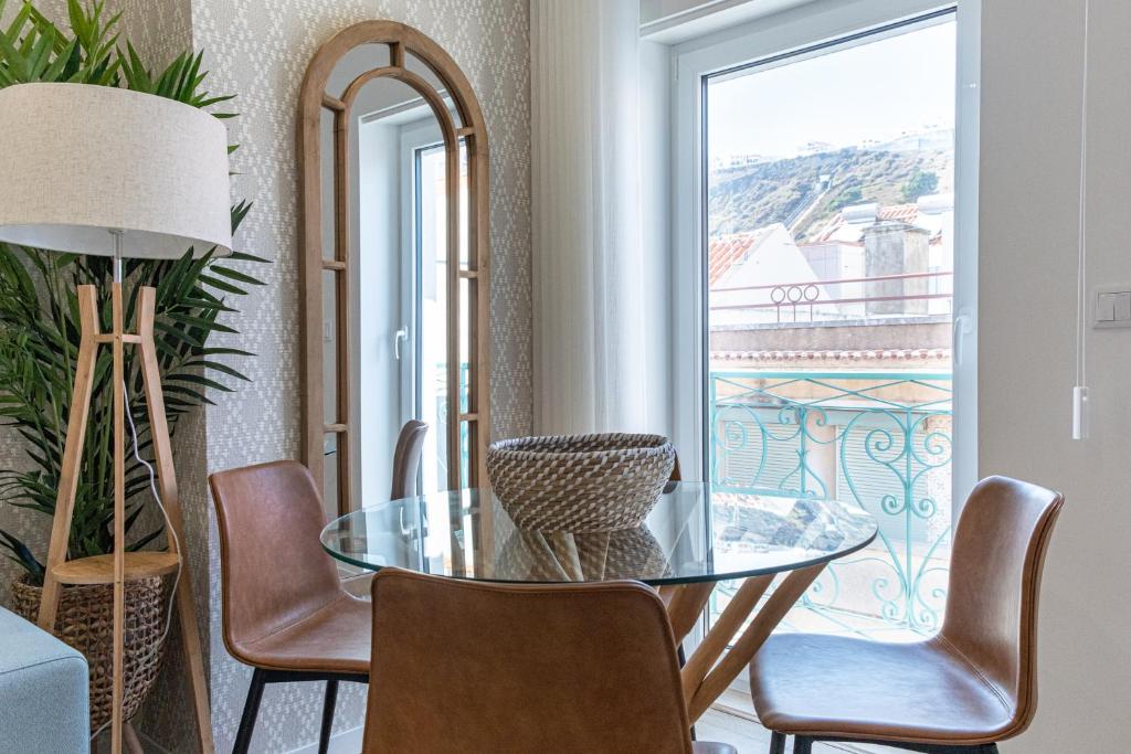 纳扎雷Feel Nazaré - Saudade 57的一间设有玻璃桌、椅子和窗户的用餐室
