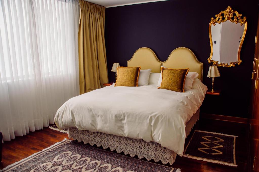 利马ANA FRANK Boutique Hotel的一间卧室配有一张大床和金色床头板
