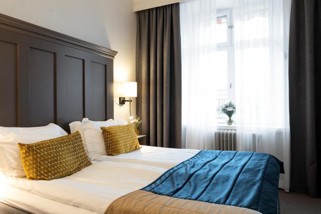 林雪平斯托拉林雪平精英酒店的一间卧室配有一张大床,提供黄色和蓝色的枕头