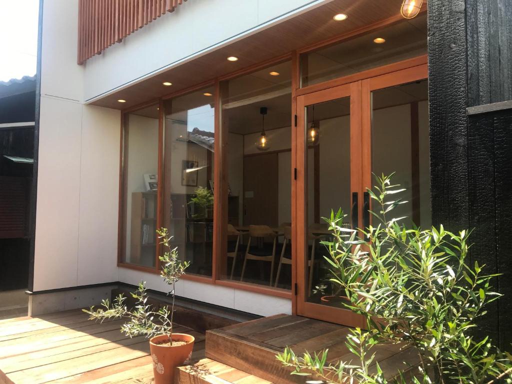 直岛町Quaint House Naoshima的门廊上装有玻璃门和植物的房子