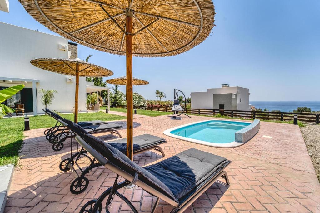 吉奥塔略Heliophos Villa Amalthia的一个带椅子和遮阳伞的庭院和一个游泳池
